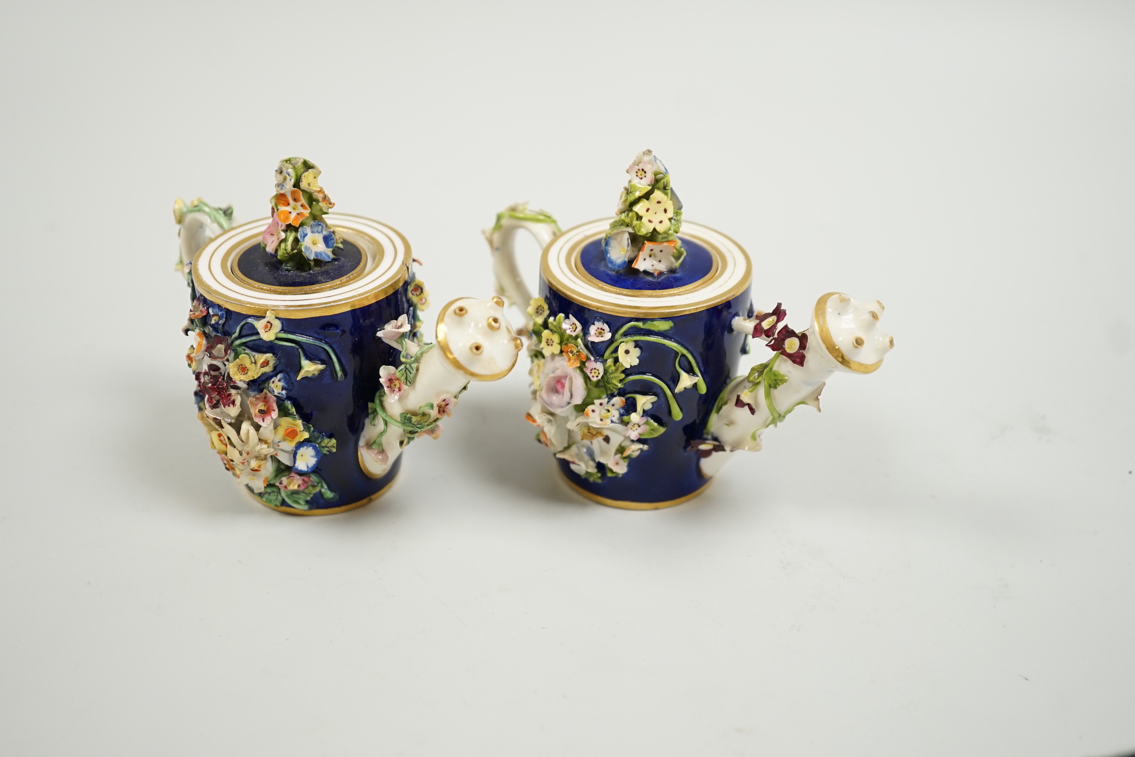 Toy porcelain. Two Bloor Derby flower encrusted rosewater sprinklers, each modelled as a watering can, c.1825, red printed marks, 9cm high